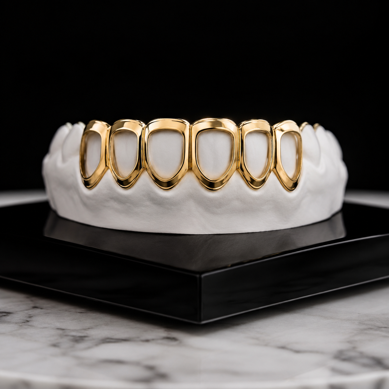 Classic Open Faces Grillz handcrafted in polished yellow gold with a raised border design displayed on a white dental mold against a luxury black studio background.